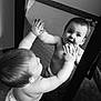 baby, black_and_white, carpet, child, curious, cute, diaper, expression, face, hands, indoor, infant, looking, mirror, playful, portrait, reflection, room, standing, young