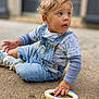 Lowen participe au concours pour gagner de l'argent avec cette photo : toddler, child, denim_overalls, toy, plastic_rings, outdoor, curious, sitting, casual_clothing, sand, playtime, blond_hair, blue_eyes, long_sleeve_shirt, footwear, young_child, daylight, casual_pose, cute, exploring