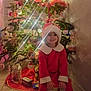 Mia participe au concours pour gagner de l'argent avec cette photo : child, christmas_tree, holiday, festive, santa_hat, red_dress, smiling, indoors, decorations, lights, ornaments, presents, floor, wall, seated, happy, celebration, seasonal, toy, festivity