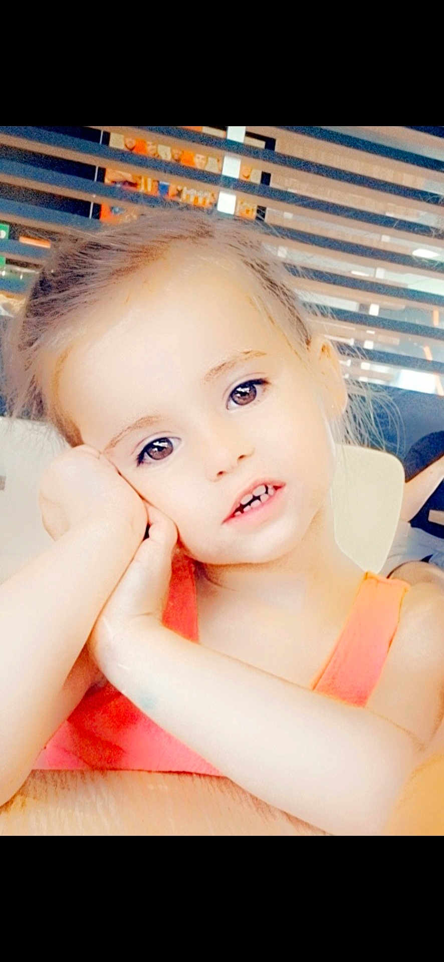 Mia participe au concours pour gagner de l'argent avec cette photo : child, face, portrait, young, girl, orange_clothing, table, resting_head, indoor, modern_interior, expression, cute, person, skin, hair, eyes, hand, sitting, casual, bright