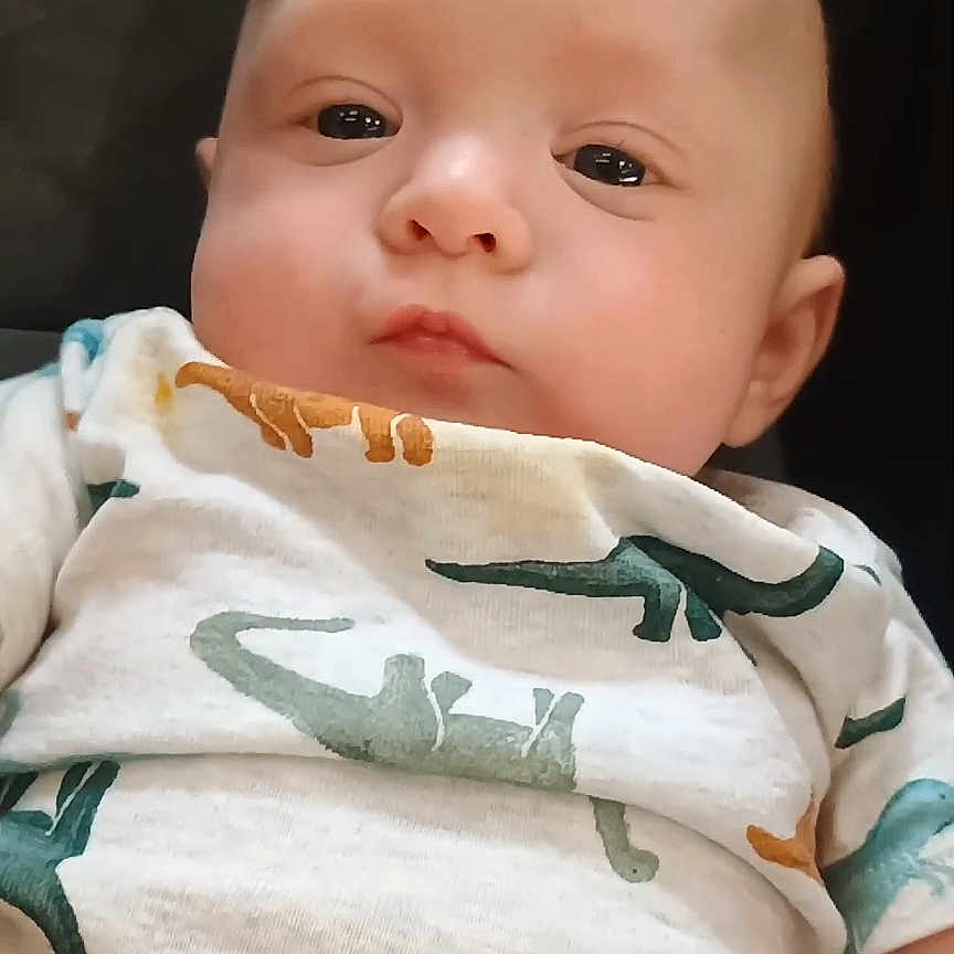 Klayse joined the competition — help win amazing prizes! adorable, baby, child, closeup, clothing, cute, dinosaur_pattern, expression, eyes, face, head, indoor, infant, lying_down, onesie, person, portrait, skin, soft_lighting, young