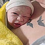 newborn, baby, infant, hat, yellow_towel, tattoo, chest, skin, close_up, expression, person, portrait, newborn_hat, newborn_wrapped, baby_face, human, indoors, soft_texture, warmth, cuddle