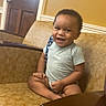 Robert is registered to the contest to win money with this photo: armchair, casual, child, clothing, cross_legged, cute, face, furniture, happy, indoor, nike, patterned_chair, person, short_sleeve, sitting, smiling, toddler, wooden_door, yellow_wall, young_child