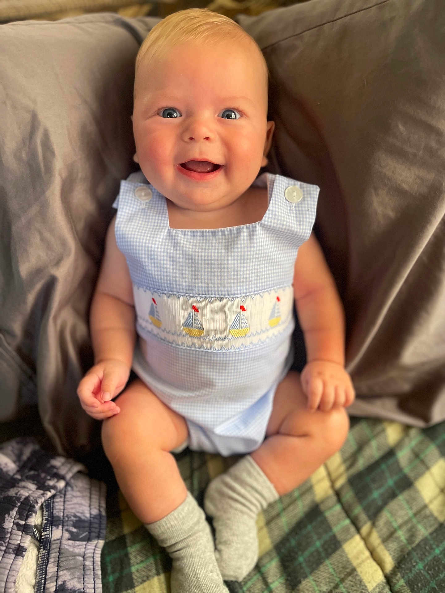 Maddox is registered to the contest to win money with this photo: baby, smiling, blue_eyes, cute_outfit, sailboat_pattern, socks, blanket, pillow, indoor, child, happy, sitting, infant, portrait, soft_lighting, closeup, comfortable, plaid_blanket, homedecor, skin