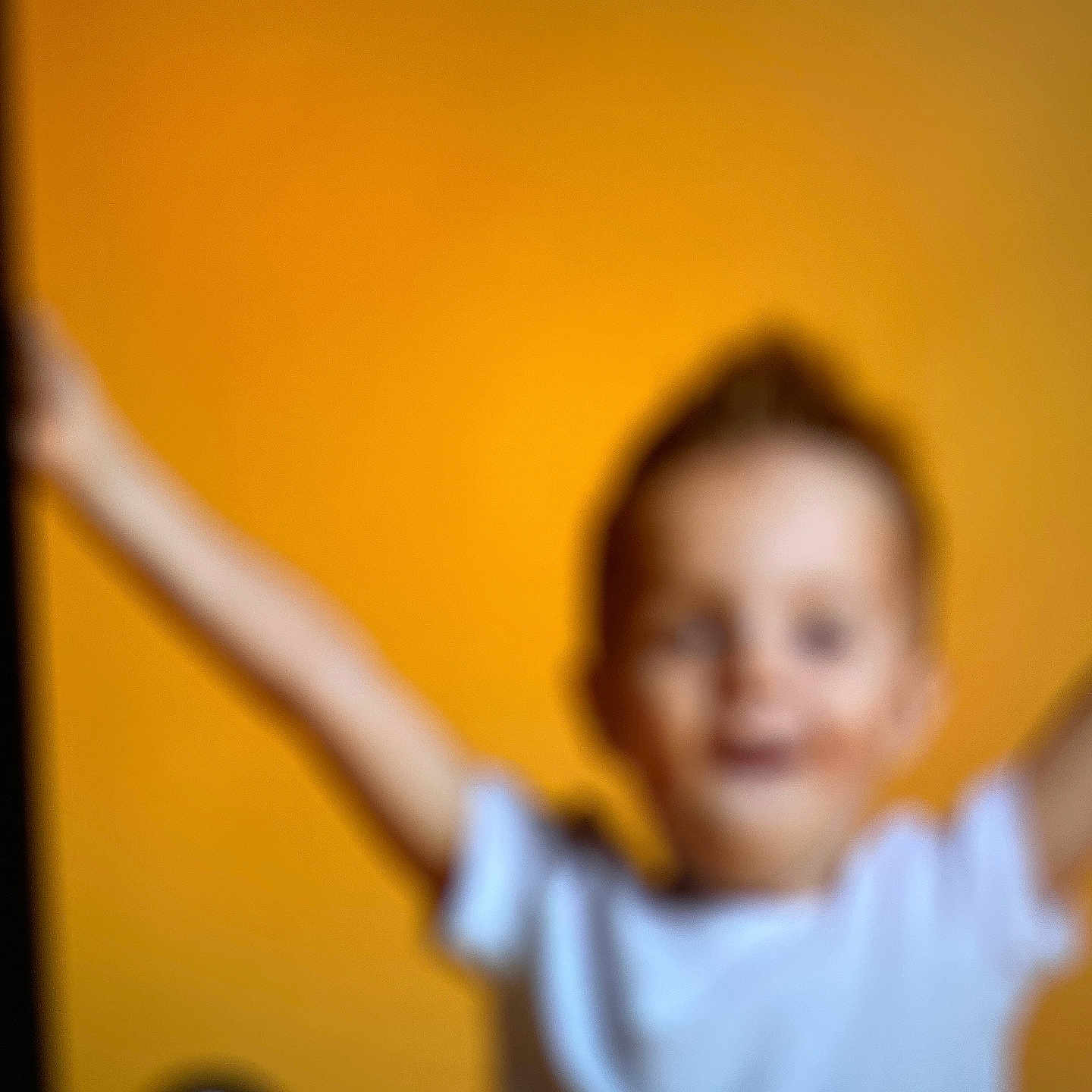 Flavia participe au concours pour gagner de l'argent avec cette photo : arms_raised, background, blur, casual, child, colorful, expression, face, head, indistinct, indoor, light, motion, orange_background, out_of_focus, person, portrait, unfocused, white_shirt, young