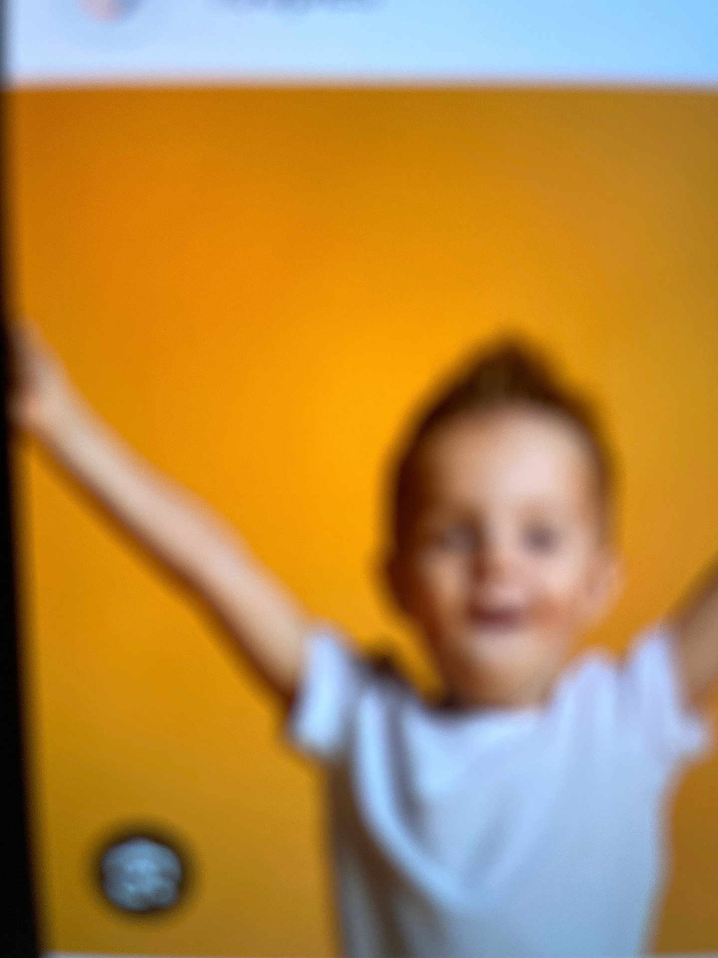 Flavia participe au concours pour gagner de l'argent avec cette photo : child, blur, orange_background, white_shirt, indoor, arms_raised, out_of_focus, portrait, person, casual, young, motion, unfocused, head, face, expression, light, colorful, indistinct, background