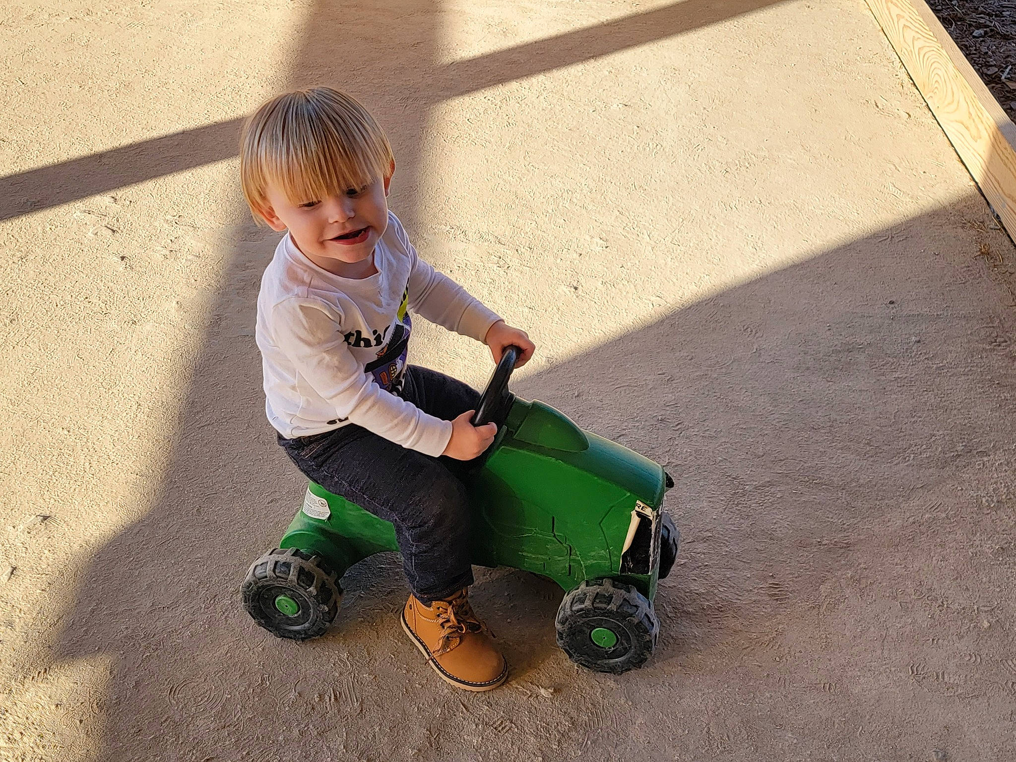 Donovan is registered to the contest to win money with this photo: asphalt, child, composite_material, concrete, driveway, fun, grass, leisure, person, play, recreation, riding_toy, road_surface, rolling, sitting, skateboard, tire, toddler, vehicle, wheel