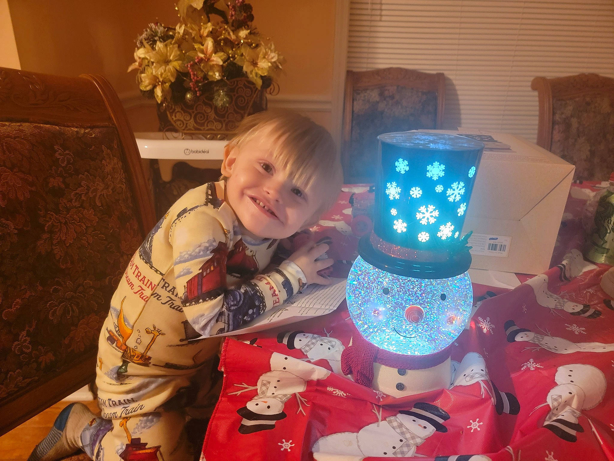 Donovan is registered to the contest to win money with this photo: baby_toddler_clothing, child, christmas, christmas_eve, comfort, drinkware, event, flower, fun, happy, holiday, home, joy, lap, living_room, party_supply, person, plant, room, sitting