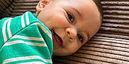 Mylan participe au concours pour gagner de l'argent avec cette photo : baby, child, closeup, couch, cozy, cute, eyes, face, green_striped_clothing, happy, head, indoors, infant, mouth, pacifier_clip, playful, portrait, skin, smiling, textured_fabric
