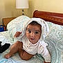 baby, child, infant, bed, bedding, blanket, pattern, white_cloth, face, eyes, hand, foot, furniture, lamp, bedroom, wood, curious, cute, sitting, indoors