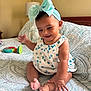 baby, child, smiling, headband, bow, anklet, bed, bedspread, pattern, indoor, furniture, lamp, happy, cute, infant, clothing, person, skin, foot, hand