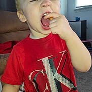 Caden joined the competition — help win amazing prizes! blinds, calvin_klein, carpet, casual_clothing, child, couch, expression, face, furniture, hair, hand, indoor, light, living_room, mouth_open, person, red_shirt, snack, window, young