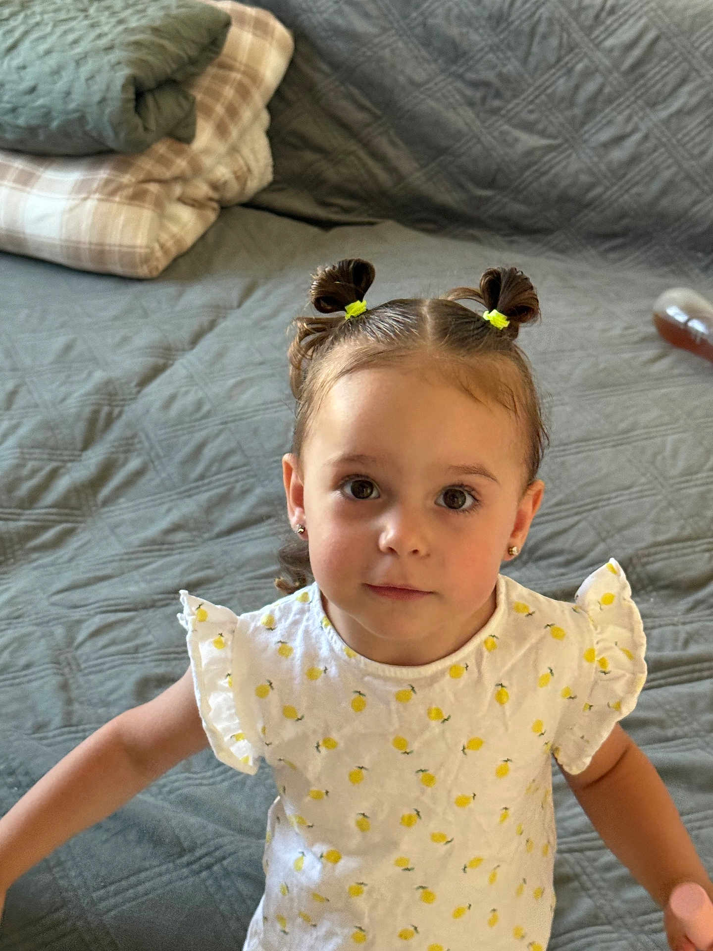 Mariana a rejoint le concours — aidez-le/la à gagner de superbes lots ! toddler, child, girl, pigtails, yellow_hair_bands, white_dress, lemon_pattern, bed, blanket, quilted_bedspread, indoor, portrait, cute, curious, face, person, young_child, earrings, looking_up, home