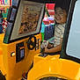child, boy, arcade, ride, yellow, smile, game, indoor, entertainment, machine, joy, happiness, play, seat, steering_wheel, screen, toy, fun, casual_clothing, footwear