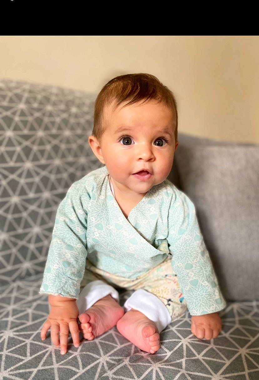 Louise participe au concours pour gagner de l'argent avec cette photo : baby, baby_toddler_clothing, cheek, child, collar, comfort, face, floor, flooring, head, iris, linens, pattern, person, portrait_photography, sitting, skin, sleeve, smile, surprise