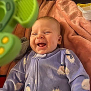 Scarlett joined the competition — help win amazing prizes! baby, blanket, child, cozy, cute, expression, face, green_toy, happy, indoor, infant, laughing, lying_down, onesie, playful, purple_clothing, smiling, snowman_print, soft_texture, toy