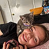 Concrete Gas Station is registered to the contest to win money with this photo: kitten, cat, person, smile, indoor, bed, pillow, blanket, face, young_person, gray_cat, cuddle, happy, closeup, casual, resting, collar, furniture, door, hand