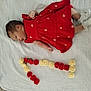 adorable, baby, child, cute, decorative, flowers, indoor, infant, lying_down, newborn, number_seven, peaceful, red_dress, resting, roses, sleeping, small_arms, sock, soft_texture, white_blanket