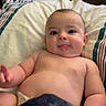 Tate is registered to the contest to win money with this photo: baby, infant, child, bed, blanket, drool, tongue, skin, cute, chubby, lying_down, indoors, pillow, striped_bedding, hand, face, head, comfort, relaxation, home
