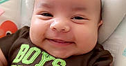 Zayden joined the competition — help win amazing prizes! baby, smiling, infant, clothing, brown_shirt, text_on_clothing, face, cheeks, cushion, seat, indoor, happy, cute, child, portrait, head, eyes, arms, baby_boy, expression