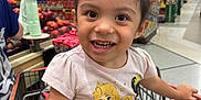 Jasmine is registered to the contest to win money with this photo: child, toddler, smiling, shopping_cart, grocery_store, clothing, hair_bun, yellow_shorts, princess_tshirt, face, person, happy, indoor, aisle, food, produce, retail, store, cute, seatbelt