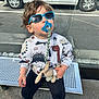 Ethan participe au concours pour gagner de l'argent avec cette photo : accessory, bench, bus_stop, casual_clothing, child, dinosaur_print, footwear, metal_bench, outdoor, pacifier, plush_toy, street, sunglasses, sunny, sweater, toddler, toy, urban, waiting, young_child