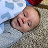 baby, infant, child, smiling, portrait, face, lying_down, blanket, gray_clothing, carpet, indoor, home, happy, eyes_open, head, pacifier, toy, floor, casual, close_up