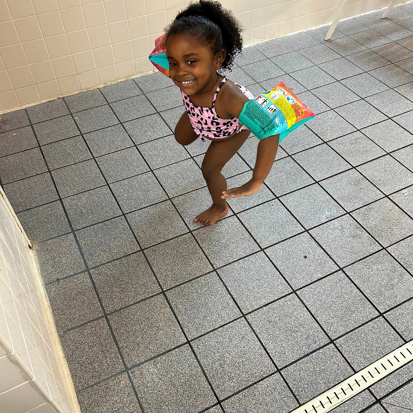 Dalilah is registered to the contest to win money with this photo: bathroom, chair, child, clapperboard, clothing, crawling, face, female, furniture, girl, head, indoors, person, photography, portrait, room, shorts, slate, swimwear, tile