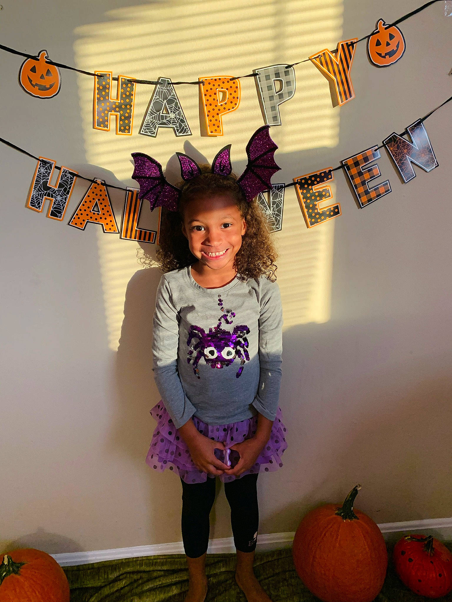 Addy is registered to the contest to win money with this photo: calabaza, child, costume, fashion_accessory, joy, orange, person, plant, pumpkin, purple, room, sleeve, t_shirt, toddler, trick_or_treat