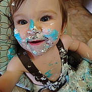 Ada joined the competition — help win amazing prizes! toddler, child, cake, frosting, messy, high_chair, smile, face, blue_frosting, white_frosting, food, happy, baby, clothing, hair, arm, table, celebration, dirt, fun