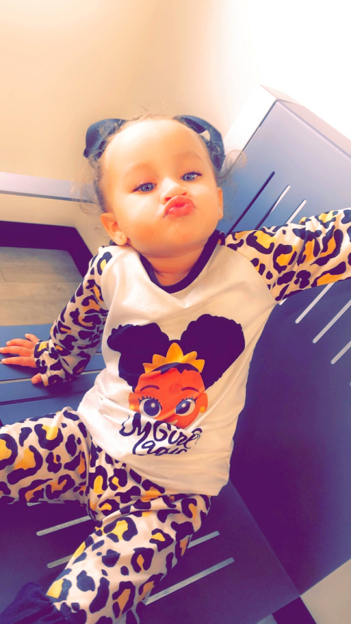Nylah is registered to the contest to win money with this photo: baby, baby_toddler_clothing, child, eye, flooring, fun, happy, head, logo, orange, pajamas, pattern, person, room, sitting, sleeve, t_shirt, toddler, top