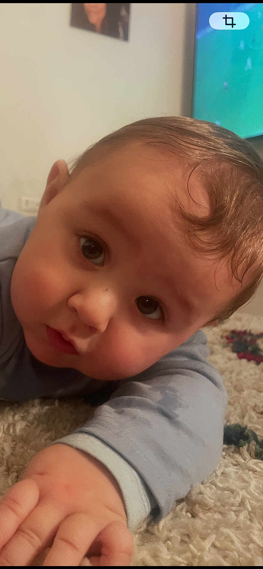 Anto Maria participe au concours pour gagner de l'argent avec cette photo : arm, baby, carpet, cheeks, close_up, cute, eyes, face, floor, forehead, gaze, hair, hand, indoor, infant, onesie, portrait, rug, sleepwear, tv_screen