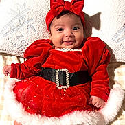 Mariel joined the competition — help win amazing prizes! baby, belt, blanket, bow, child, chubby_cheeks, cute, festive, fluffy_trim, happy, headband, holiday_outfit, indoors, infant, lying_down, portrait, red_dress, smiling, snowflake_pattern, velvet