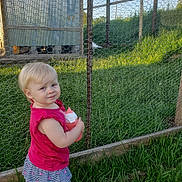 Charlotte is registered to the contest to win money with this photo: baby, backyard, ball, clothing, dress, face, fence, football, grass, head, nature, outdoors, person, photography, plant, portrait, soccer, soccerball, sport, yard