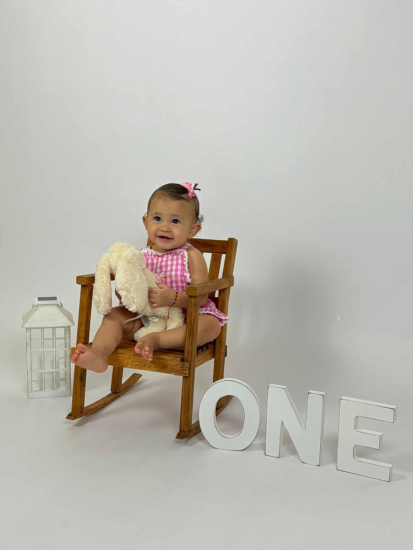 Aleah Calderon is registered to the contest to win money with this photo: baby, child, rocking_chair, stuffed_animal, bunny, pink_dress, hair_bow, smile, wooden_furniture, lantern, white_background, one, milestone, celebration, cute, portrait, sitting, happy, indoor, person