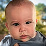 baby, close_up, face, blue_shirt, hand, outdoor, portrait, child, infant, skin, eyes, expression, person, young_child, head, cute, natural_light, background_blur, fingertip, soft_focus