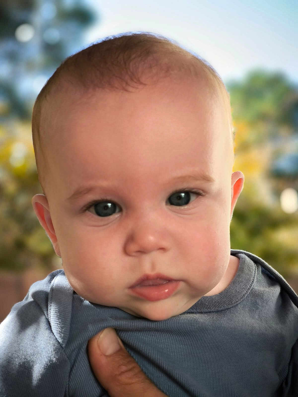 Raoul a rejoint le concours — aidez-le/la à gagner de superbes lots ! baby, close_up, face, blue_shirt, hand, outdoor, portrait, child, infant, skin, eyes, expression, person, young_child, head, cute, natural_light, background_blur, fingertip, soft_focus