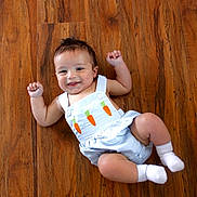 Colsen is registered to the contest to win money with this photo: baby, child, infant, smiling, wooden_floor, romper, carrot_design, white_socks, playful, happy, cute, indoor, person, skin, head, arms, legs, clothing, flooring, portrait