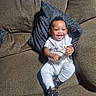 baby, smile, couch, pillow, clothing, footwear, infant, happy, indoor, person, sitting, comfortable, child, cute, young, portrait, casual, home, relaxing, toy