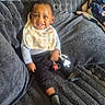 Montrell is registered to the contest to win money with this photo: baby, child, smiling, bib, toy, couch, cushion, blanket, clothing, indoors, happy, person, sitting, portrait, face, cozy, furniture, sock, home, infant