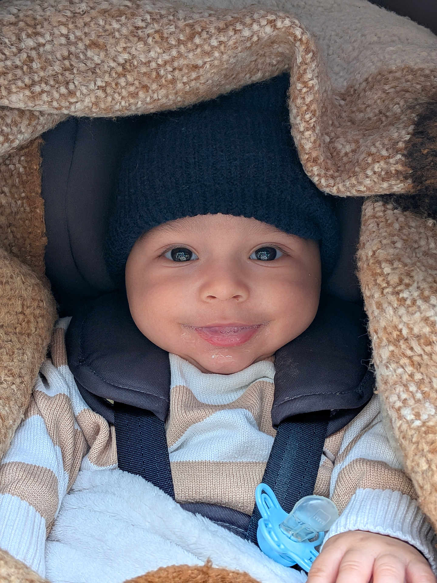 Soan participe au concours pour gagner de l'argent avec cette photo : baby, child, smiling, face, hat, knitwear, striped_clothing, blanket, pacifier, hand, closeup, infant, warm, cozy, cute, comfort, seatbelt, portrait, indoors, baby_clothing