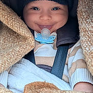 Soan participe au concours pour gagner de l'argent avec cette photo : baby, smile, pacifier, knitwear, blanket, hat, car_seat, child, cozy, striped_sweater, infant, clothing, happy, portrait, warm, cute, seatbelt, closeup, person, bundle