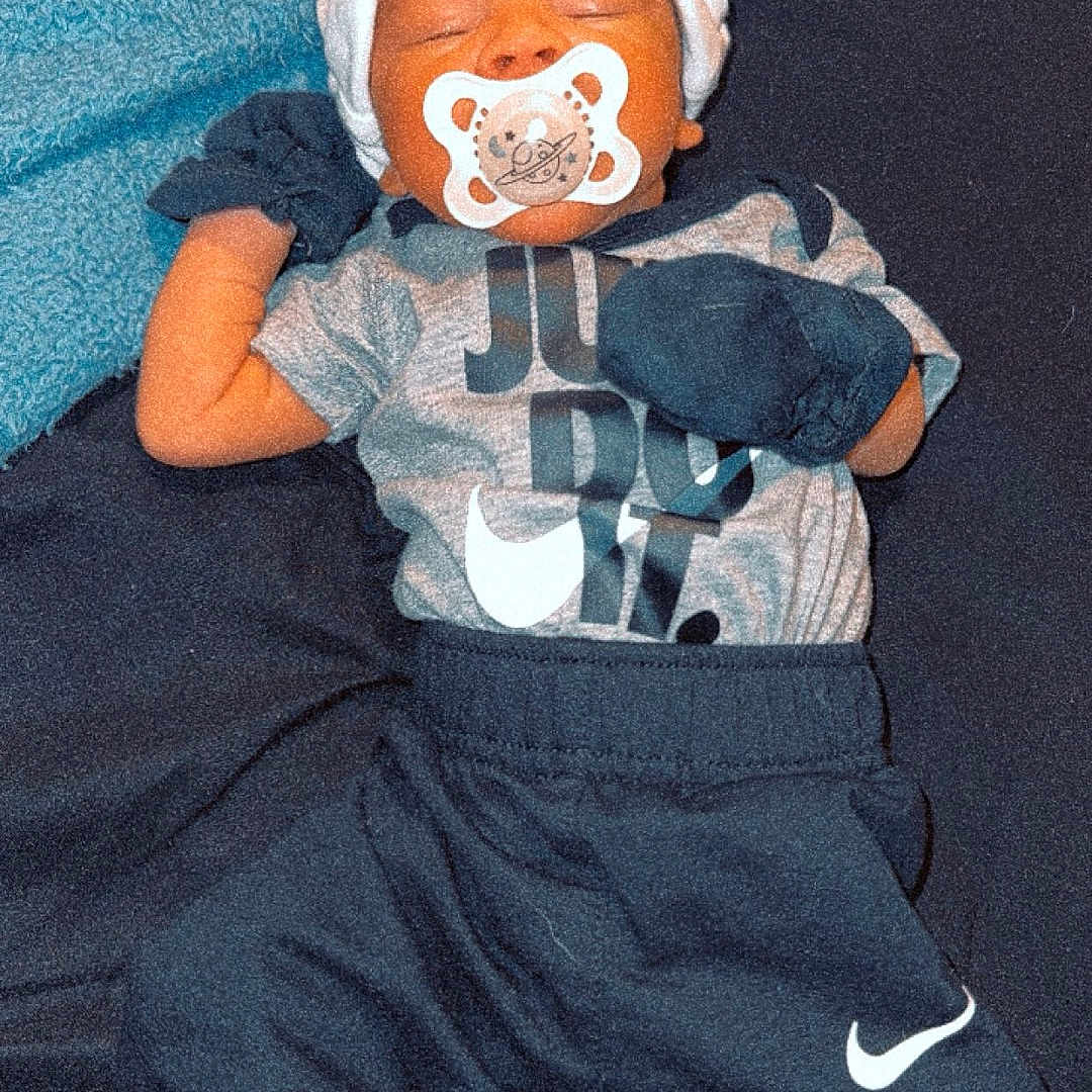 Latrell is registered to the contest to win money with this photo: baby, bonnet, clothing, costume, couch, face, footwear, furniture, glove, hat, head, hosiery, pants, person, photography, portrait, shoe, sleeping, sock, toy