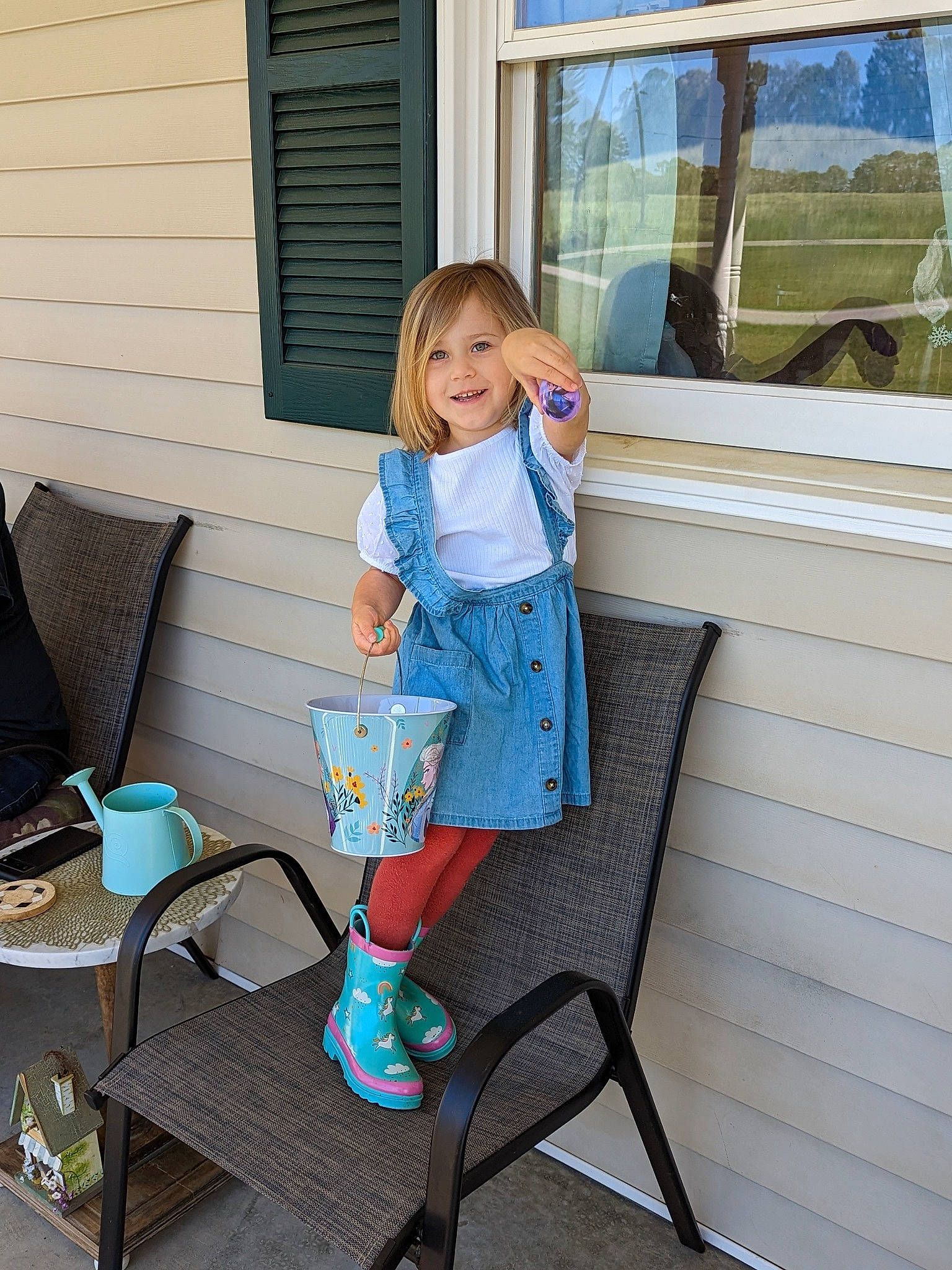 Madison is registered to the contest to win money with this photo: baby_toddler_clothing, blue, chair, door, electric_blue, foot, house, human_leg, joy, knee, leisure, outdoor_furniture, pattern, person, room, sandal, sitting, smile, standing, toddler