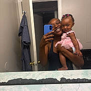 Lady joined the competition — help win amazing prizes! woman, baby, child, mirror, selfie, bathroom, tutu, pink, smile, happy, holding, door, robe, phone, reflection, hair, skin, clothing, cute, portrait