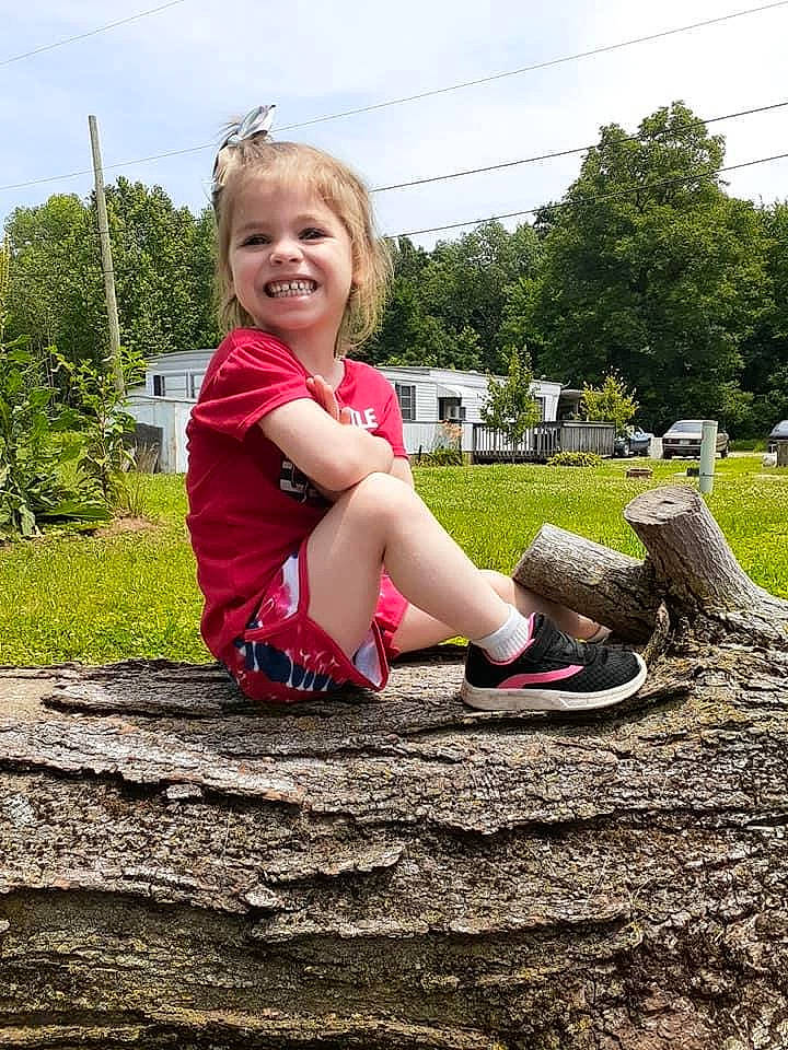 Samantha is registered to the contest to win money with this photo: child, fun, grass, happy, joy, leg, person, photography, pink, plant, play, playground, public_space, recreation, red, sitting, smile, soil, summer, toddler