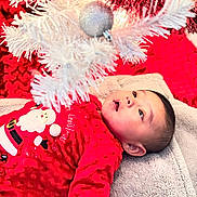 Omar is registered to the contest to win money with this photo: baby, blanket, celebration, child, christmas, cozy, cute, decor, face, festive, gazing, holiday, indoor, infant, ornament, red_clothing, santa_outfit, silver_ball, soft_texture, white_tree