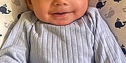 Omar is registered to the contest to win money with this photo: baby, infant, smiling, face, blue_clothing, whale_pattern, blanket, cute, child, portrait, lying_down, young_child, happy, indoors, one_person, closeup, skin, head, eyes, small_scratch