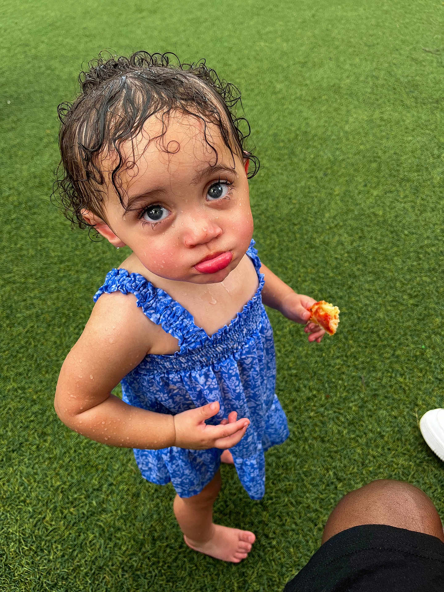 Kmayrah is registered to the contest to win money with this photo: toddler, child, wet_hair, blue_dress, pizza, barefoot, grass, outdoor, pout, curly_hair, summer, cute, food, expression, person, standing, looking_up, skin, small_hand, playful