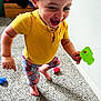 Kmayrah joined the competition — help win amazing prizes! toddler, child, yellow_shirt, floral_leggings, toy, green_toy, carpet, indoor, happy, smiling, barefoot, motion, curly_hair, playtime, furniture, clothing, person, home, floor, colorful